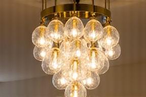 Lampadario moderno a cascata in ottone lucido con lampade a bulbo in vetro opaco.