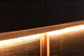 Dettaglio di una fonte luminosa integrata in una boiserie di legno scuro.
