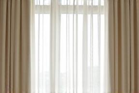 Tenda di lino pesante color avorio con pieghe perfette che copre una grande finestra.